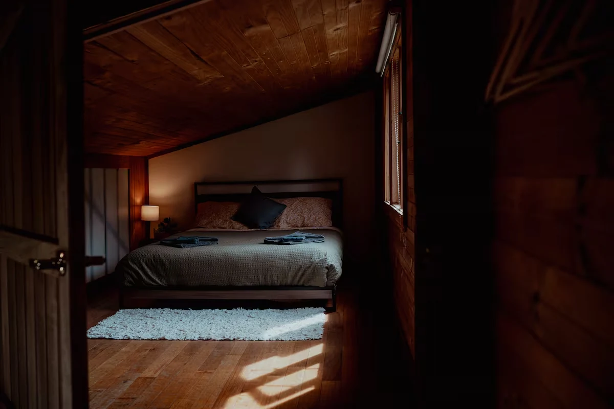 Warm queen bedroom tucked beneath the timber roof